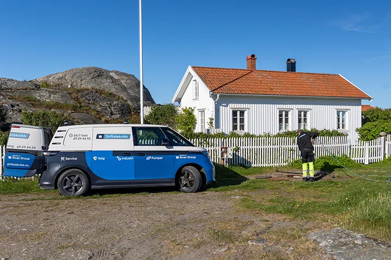 Ansatt og firmabil utenfor hytte